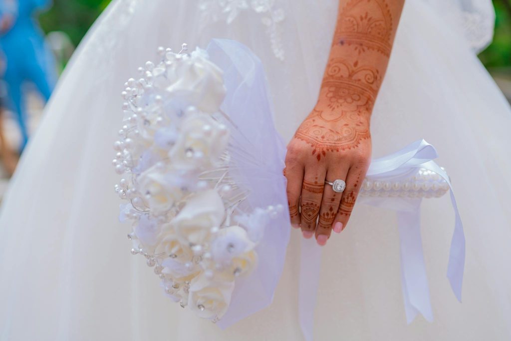 Bride with henna-decorated hand holding a floral bouquet in Paris.