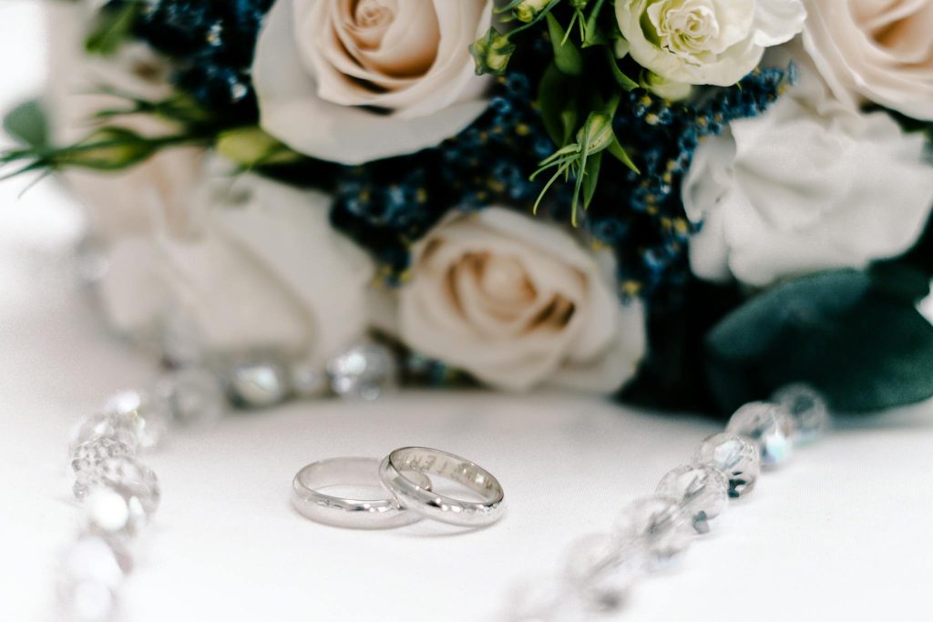 Close-up of wedding rings and a beautiful floral bouquet, perfect for romance and wedding themes.