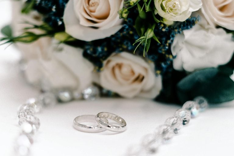 Close-up of wedding rings and a beautiful floral bouquet, perfect for romance and wedding themes.