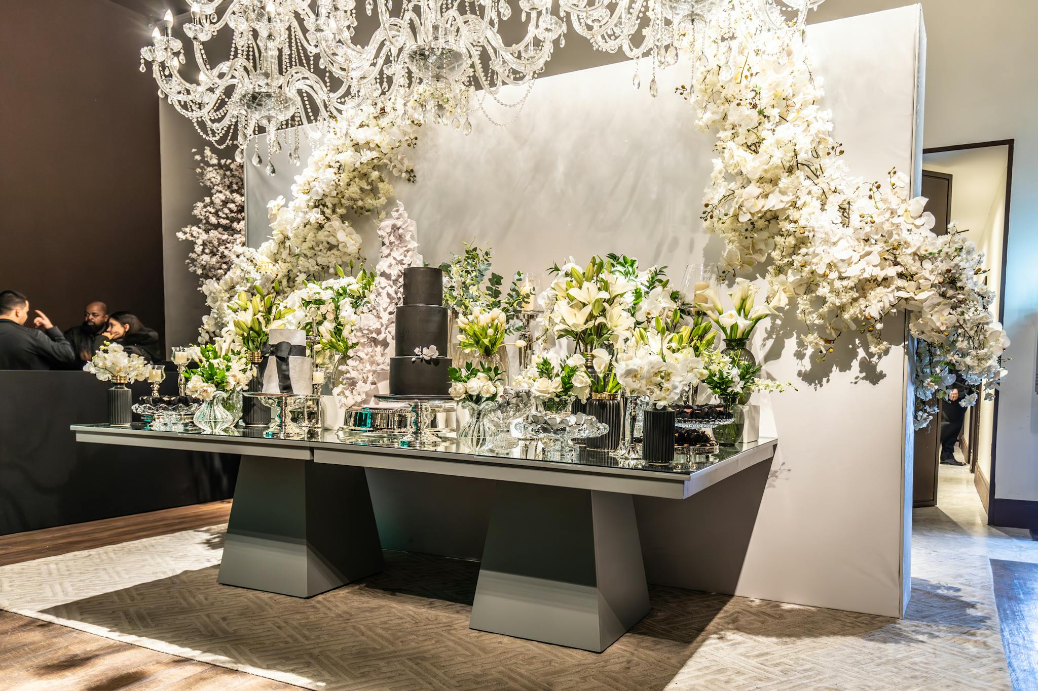 Elegant wedding decor featuring a lavish floral arrangement and chic black wedding cake.